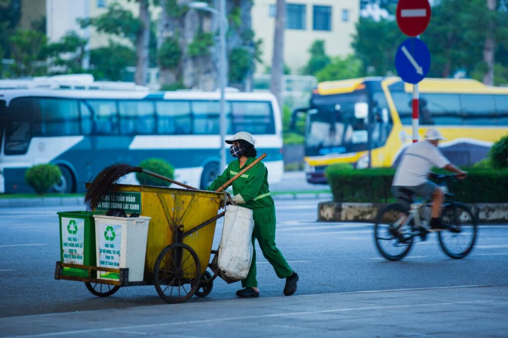 Mastering the First Impression: Your intriguing post title goes here Street cleaner pushing cart with recycling bins in a busy urban setting.