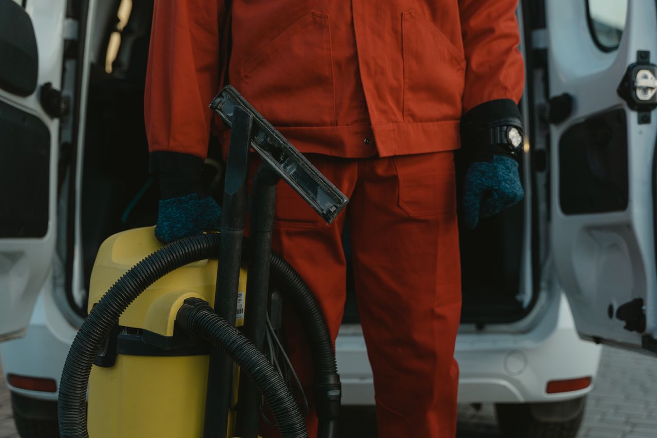 Crafting Captivating Headlines: Your awesome post title goes here A professional cleaner in a red uniform holding a vacuum near a van, ready for service.